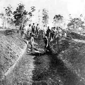 Bodies being buried in trenches.